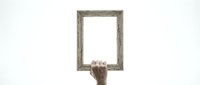 Hand holding empty wooden picture frame against white background isolated for design and creative projects.