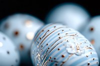 Elegant light blue Christmas baubles with rose gold glitter pattern and delicate swirls on dark background, festive holiday decoration macro photography.