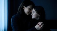 Tender moment between mother and daughter embracing by window in soft natural light creating intimate family bonding scene for emotional storytelling.