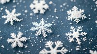 White delicate snowflakes scattered on dark blue textured background with soft focus and bokeh effect creating winter holiday atmosphere.