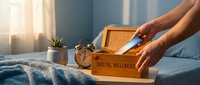 Hands opening wooden digital wellness box on bed with morning sunlight streaming through window, promoting healthy technology habits and mindful living.