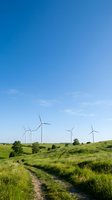 Wind turbines dotting green rolling hills with clear blue sky, representing renewable energy generation and sustainable power solutions for environmental conservation.