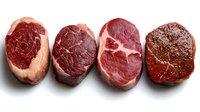 Raw beef steaks variety showing different cuts and marbling patterns arranged in row on white background for culinary and cooking concepts.