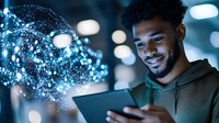 Young African American man in hoodie smiling while using digital tablet with glowing blue particle effect emerging from screen, bokeh lights in background.