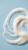 Creamy foam swirl with bubbles on soft blue background for skincare and beauty product advertising campaigns.