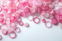 Sliced red onion rings scattered on white background creating organic pattern composition. Fresh vegetable pieces arranged with soft pink tones and transparency.