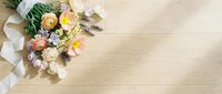 Soft spring bouquet with pastel ranunculus, tulips, and lavender on a light wooden surface with a white ribbon and copy space.