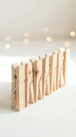 Row of wooden clothespins arranged in line on white surface with warm bokeh lights creating cozy atmosphere for laundry and household organization concepts.