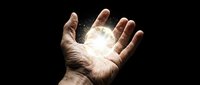 Open hand with bright glowing light emanating from palm against dark background, symbolizing power, energy, magic, spirituality and divine connection.