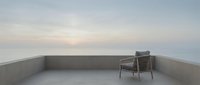 Minimalist rooftop terrace with single woven chair overlooking serene horizon at dawn, conveying solitude and contemplation for wellness and lifestyle design projects.