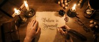 Hand writing motivational quote believe in yourself on parchment paper with vintage candles and quill pen creating warm atmospheric workspace for inspiration.