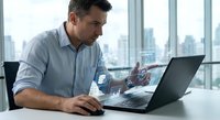 Professional businessman analyzing financial data and charts on laptop computer in modern office with city skyline view for business analytics and reporting.