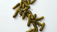 Pickled gherkins and cornichons scattered on white background, ready for food packaging, recipe blogs, culinary design, restaurant menus and grocery advertising.
