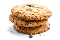 Stack of freshly baked chocolate chip cookies with crispy edges and soft centers on white background, showing texture and chocolate chunks. Food photography.