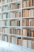 Modern white bookshelf filled with vintage books in pastel and neutral tones, creating an elegant home library atmosphere for interior design projects.