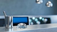 Modern kitchen counter with stainless steel utensil holder and glass bowl on marble surface. Contemporary home interior design with blurred appliances background.
