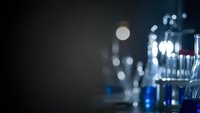 Blurred laboratory glassware and equipment with bokeh lights creating atmospheric scientific research background for medical and chemistry presentations.