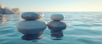 Zen stones balanced on calm turquoise water surface at sunrise, creating peaceful reflection. Meditation and wellness concept for spa and relaxation background.