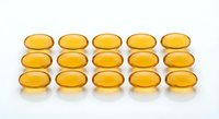 Golden omega-3 fish oil capsules arranged in neat rows on white background. Dietary supplements for heart health and wellness nutrition.