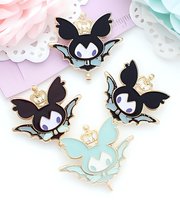 Cute kawaii bat enamel pins with crown design on pastel background. Black and mint colored fantasy creatures for accessories and collectibles market.