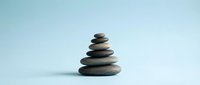 Balanced stack of smooth river stones creating zen meditation tower on clean white surface for wellness and mindfulness concepts.