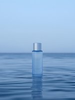 Blue cosmetic bottle floating on calm water surface with serene sky background for skincare and beauty product advertising campaigns.