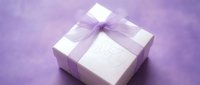 White gift box with purple ribbon bow and Happy Birthday inscription on soft lavender background, perfect for celebration and holiday greeting concepts.