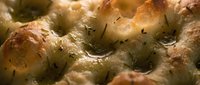 Freshly baked bread rolls with golden-brown crust and herb seasoning, close-up food photography for bakery, culinary, and recipe content.