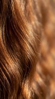 Close-up of shiny brown hair strands with golden highlights and natural texture showing healthy hair care and beauty treatment results.