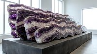 Large purple amethyst geode crystal formation with natural banded layers displayed on dark platform in modern interior space for geology education.