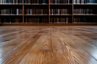 Polished wooden floor in library with blurred bookshelves background, low angle perspective creating dramatic depth and leading lines toward literature collection.