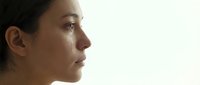 Young Middle Eastern woman crying, tear on cheek, side profile close-up, emotional pain and grief concept on light background.