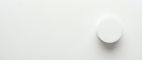 White round pill or tablet on clean beige background with copy space for medical and pharmaceutical design projects.