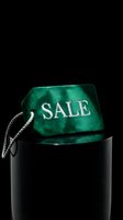 Luxury green velvet sale tag with silver embroidery on dark background, evoking premium retail discount and exclusive shopping event.