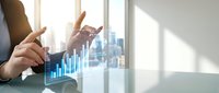 Businessman analyzing financial growth charts on digital tablet with city skyline background showing data visualization and business analytics success.