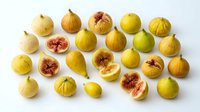 Yellow figs whole and halved arranged on white background, showing fresh red interior flesh and seeds. Suitable for food styling, culinary content, healthy eating campaigns, recipe blogs, and nutritional product packaging.