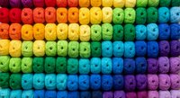 Colorful rainbow yarn skeins arranged in gradient rows from red to purple, perfect for knitting, crochet projects and textile crafts display.