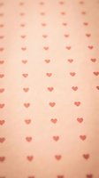 Seamless repeating pattern of small red hearts on soft peachy background, tiles continuously for wallpaper and textile design applications.