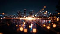 Modern cityscape at night with glowing light trails and bokeh effect, urban skyline reflected in water surface creating dynamic motion perspective.