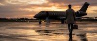 Business executive walking toward private jet at sunset on wet tarmac. Corporate travel, luxury lifestyle, success concept for presentations and marketing.