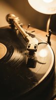 Vintage turntable with tonearm and vinyl record in warm sepia lighting creating nostalgic atmosphere for music and audio equipment concepts.