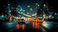 Blurred city street at night with colorful bokeh lights from traffic and buildings creating atmospheric urban scene with wet asphalt reflecting illumination.