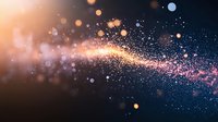 Magical glowing particles with orange and pink light trail effect on dark background, creating ethereal bokeh and sparkle atmosphere for festive designs.