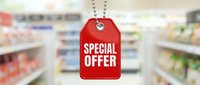 Red special offer price tag hanging on chain against blurred supermarket aisle background, retail sale promotion concept.