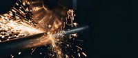 Industrial metal cutting with angle grinder creating bright sparks and flames in workshop environment for manufacturing and metalworking projects.