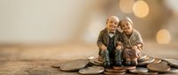 Elderly couple figurines sitting on scattered coins with warm bokeh lights background representing retirement savings and financial planning for seniors.