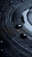 Water drops on dark circular textured surface creating abstract pattern with light reflection and bokeh effect in monochromatic style.