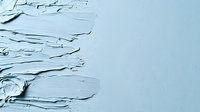 Textured light blue paint strokes with thick impasto technique creating dimensional surface with rough edges and layered application on canvas background.