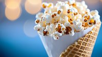 Fresh popcorn served in a waffle cone against blurred blue background with bokeh lights, creative snack presentation for movie nights or parties.