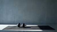 Dumbbell weight on black exercise mat against gray concrete wall background for fitness and gym training concepts.